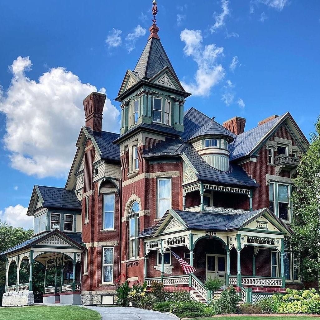 Grand Victorian mansion with turret, wraparound porch, and ornate architectural details against blue sky