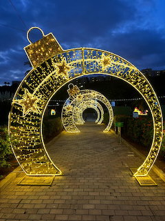 Golden holiday light tunnel archway over brick path at twilight