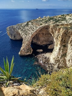 Limestone cliffs and natural rock arches at the Blue Grotto with turquoise sea below