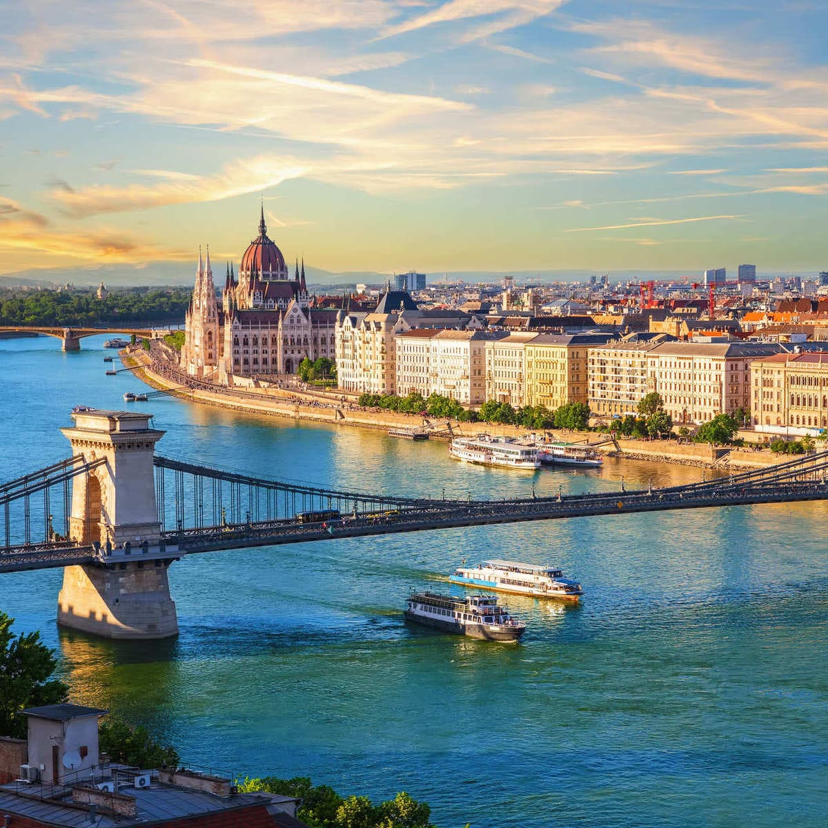 Sunset view of Budapest with Parliament Building, Chain Bridge, and Danube River with boats