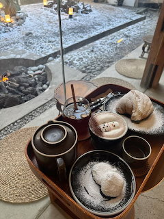 Traditional tea set and pastries on a wooden tray by a window with a snowy courtyard outside