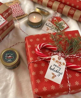 Red Christmas gift with candy canes, pine, holiday tag, candles and red twine