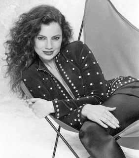 Black-and-white portrait of Fran Drescher reclining in a chair wearing a dark studded outfit
