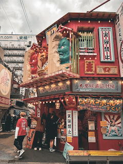 Traditional decorated Japanese storefront with red ornate facade and lanterns in Osaka street scene