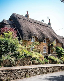 Traditional English cottage with thick thatched roof and garden