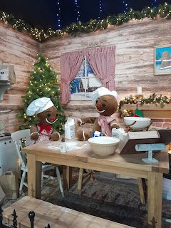 Miniature gingerbread kitchen decorated for Christmas with tree, table, and festive garland
