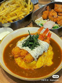 Japanese curry omurice with cream topping and crab legs,fried chicken and fries on a restaurant table