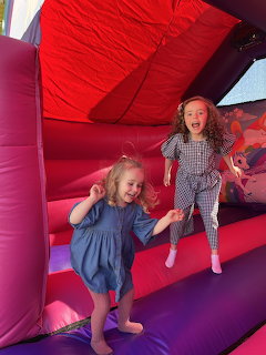 Two young girls playing inside a pink and red inflatable bounce house