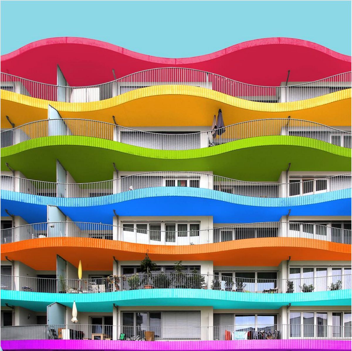 Modern building with colorful horizontal wavy stripes in rainbow colors and white balconies