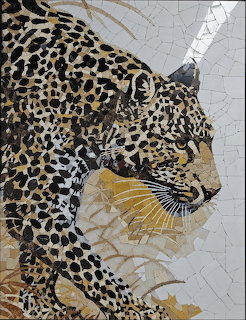 Mosaic artwork of a leopard and cub made from small stone tiles in gold, black, and cream colors
