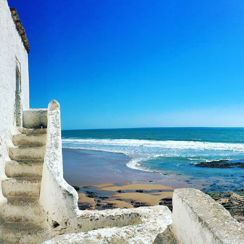 Whitewashed steps beside a sandy beach and blue ocean under a clear sky
