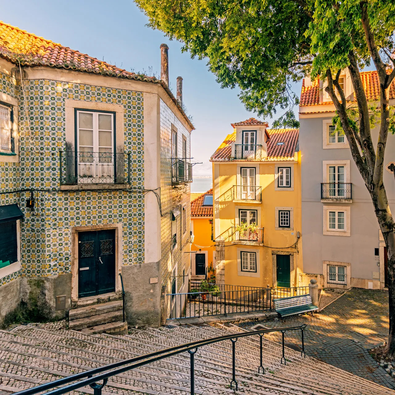 Sunny Lisbon street with tiled buildings, cobblestone walkway, and trees