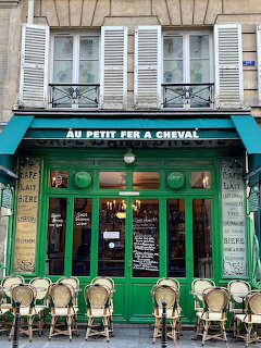 Au Petit Fer à Cheval café in Paris with green storefront and rattan chairs lined outside