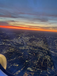 Aerial sunset view of illuminated city with rivers seen through airplane window