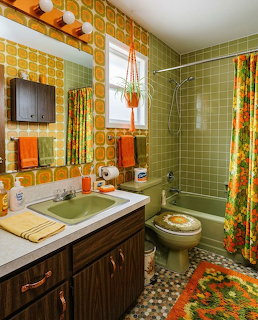 Retro 1970s bathroom with green tiles, orange wallpaper, floral curtain, and vintage fixtures
