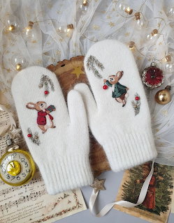 White knitted mittens with embroidered mice on sheet music and festive winter decor