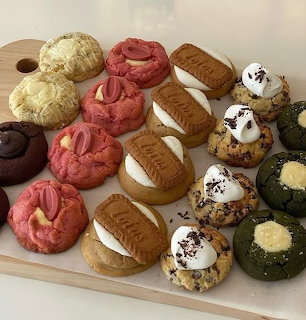 Wooden board with rows of assorted colorful gourmet cookies in many flavors