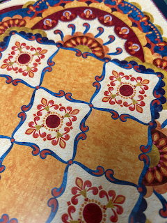 Close-up of a decorative quilt with floral patchwork squares in red, blue, cream, and gold
