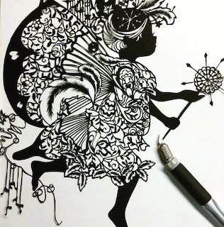 Detailed black paper cut art of woman's profile with intricate floral and geometric pattern filling