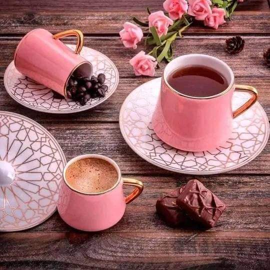 Pink tea and coffee cups with saucers, dates, berries, and roses on a wooden table