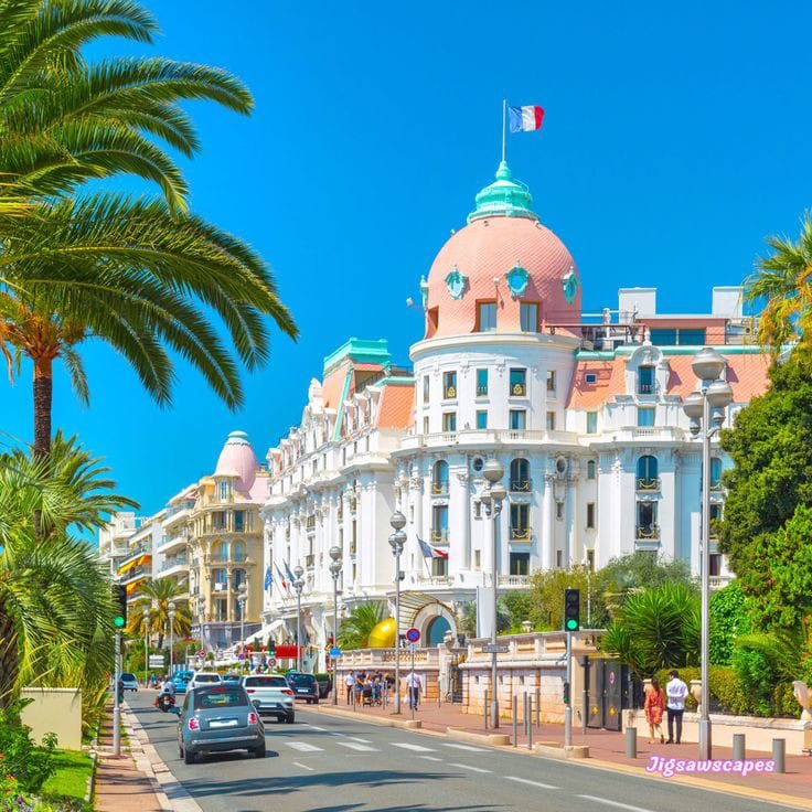 Pink-domed Hotel Negresco building on palm-lined promenade in Nice, France under blue sky