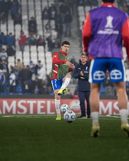Soccer player in red uniform preparing to kick ball during stadium warm-up session