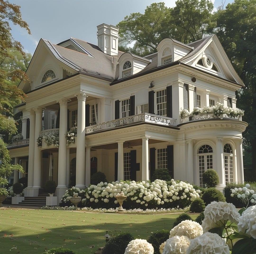 White colonial mansion with columns and hydrangeas in front yard