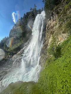 Waterfall flowing down rocky cliff with green moss and blue sky