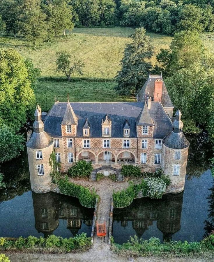 Aerial view of a French castle with turrets surrounded by a moat and green fields