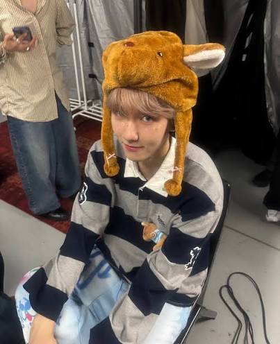 Person in striped hoodie wearing brown plush animal hat with dangling ear flaps