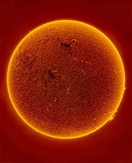 Close-up solar telescope view of the sun showing surface texture and dark sunspots