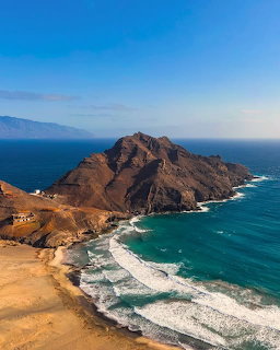 Aerial view of rocky peninsula surrounded by ocean waves and beach