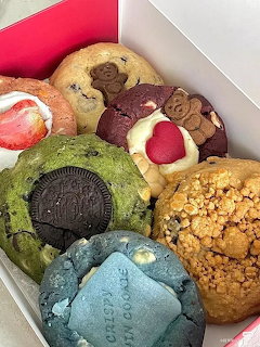 Assorted colorful donuts with various toppings in a white box
