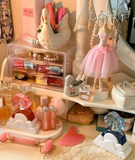 Feminine vanity table with perfume bottles, balerina figurine, pearl jewelry, and pink coquette decor