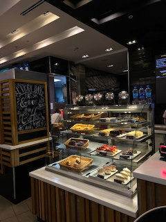 Modern cafe counter with glass food display case, pastries, and chalkboard menu sign