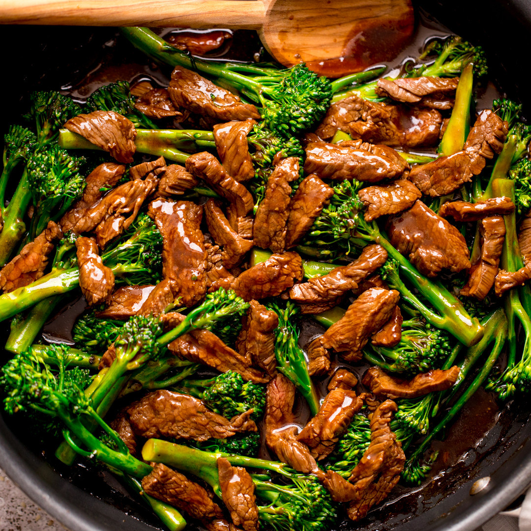 Beef strips and broccoli florets in a pan with glossy brown sauce