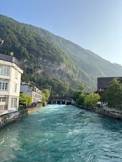 Turquoise river through Interlaken Switzerland with buildings and forested mountain backdrop