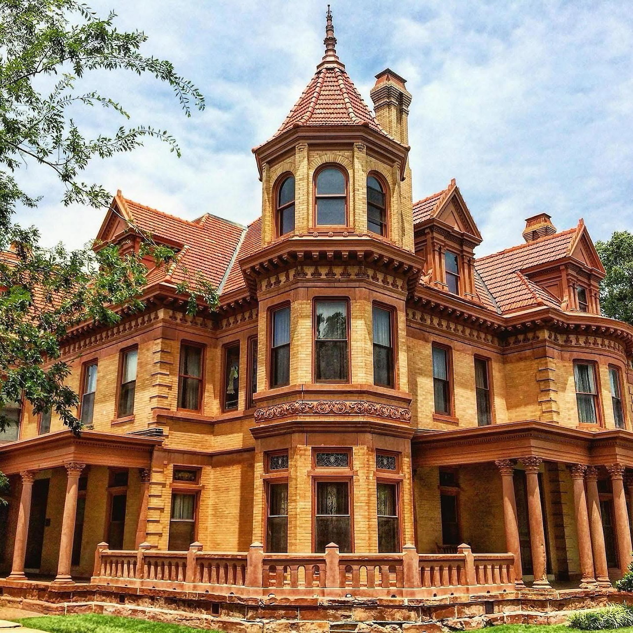 Grand Victorian mansion with red roof, turret, and ornate architectural details