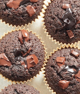Close-up of chocolate cupcakes with chocolate topping and chocolate chunks in paper liners.