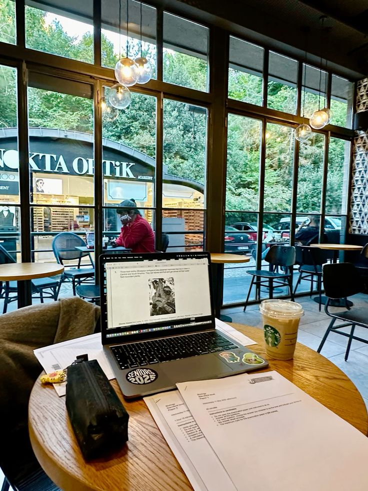 Laptop and iced coffee on a café table by large windows with street view