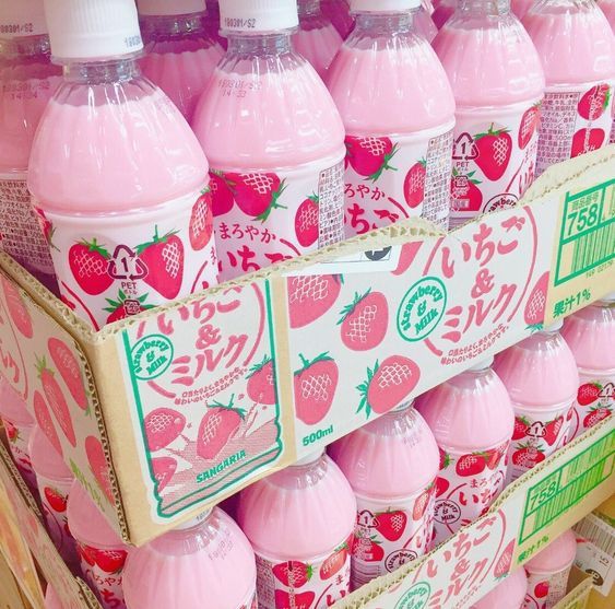 Pink strawberry milk bottles with cute strawberry-decorated labels on a store shelf