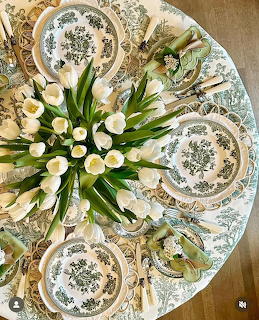 Aerial view of round table with white tulip centerpiece, green toile plates, and elegant place settings