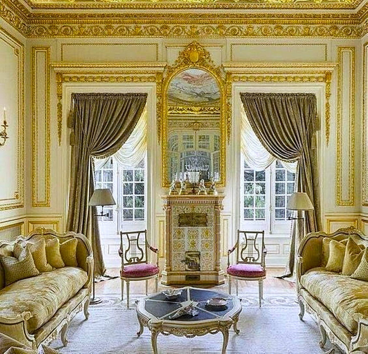 Formal French-style sitting room with sofas, draped windows, ornate moldings, and a fireplace mirror