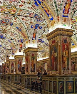 Grand Vatican library with elaborate painted ceiling, ornate columns, and antique wooden furniture on checkered marble floor