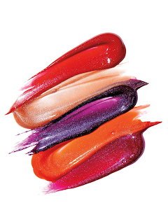 Colorful lipstick and lip gloss swatches in red, nude, purple, and orange on white
