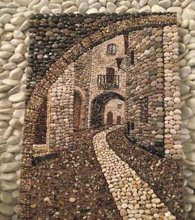 Pebble mosaic art depicting a village aleyway with stone buildings and arched walkways