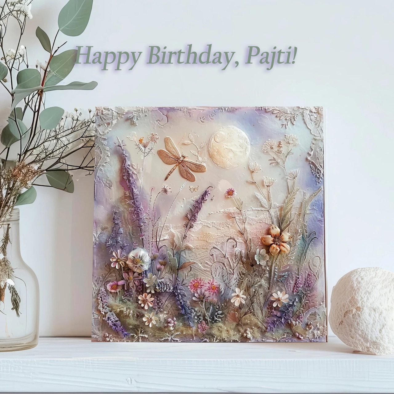 Framed dried flower art with purple blooms, eucalyptus, ceramic vase and candle on white shelf