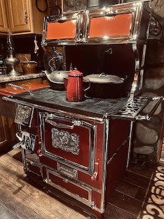 Red vintage cast iron stove in a rustic kitchen with cookware and wooden cabinets