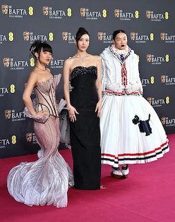 Rei Ami, EJAE, and Audrey Nuna posing together on the BAFTA red carpet in elegant outfits.
