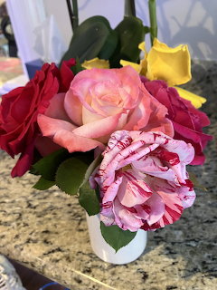 Bouquet of pink, red, and yellow garden roses in a white vase on a granite countertop